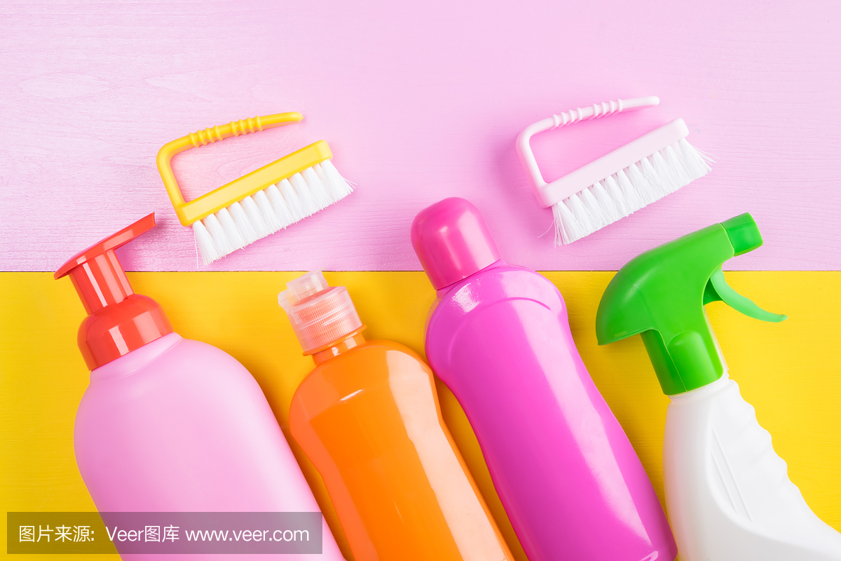 概念从彩色瓶子与清洁产品和刷子清洁在一个粉红色的黄色背景